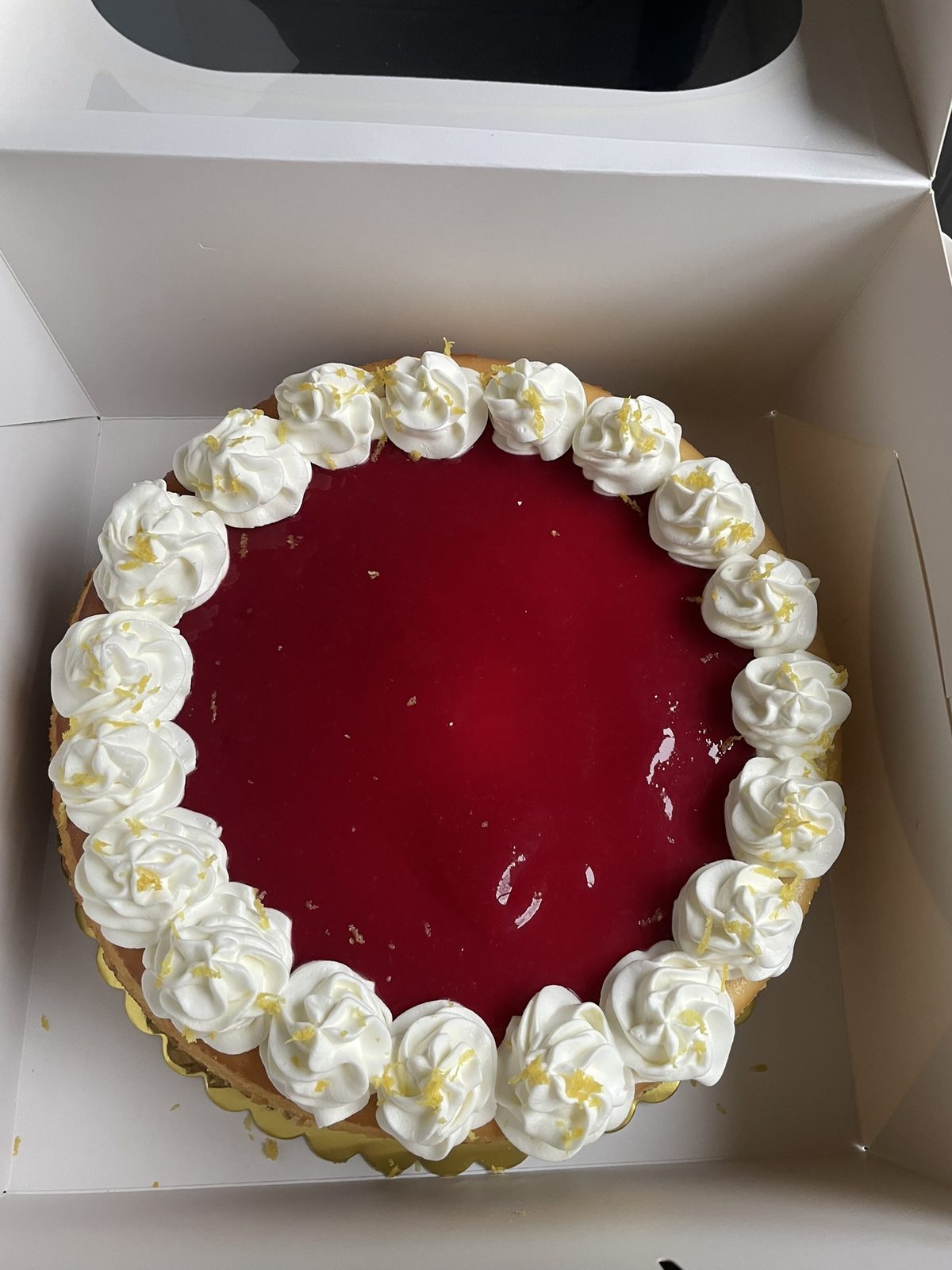 Raspberry cheesecake with a mirror glaze and piped cream rosettes