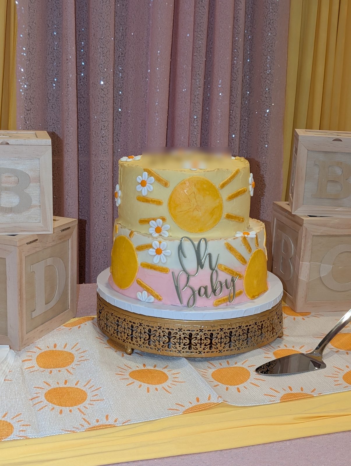 Two-tier sunshine and daisy baby shower cake on a gold stand